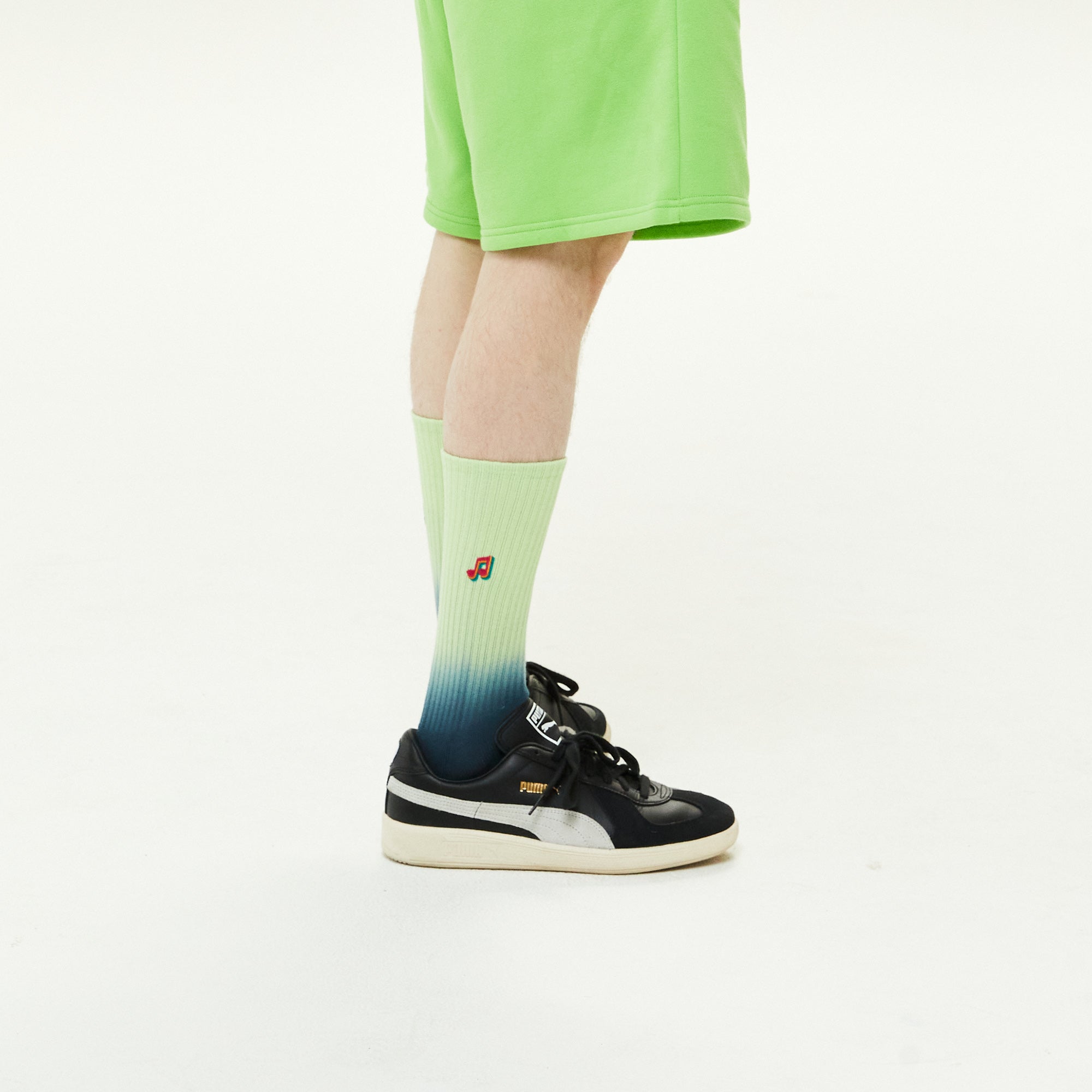A person wearing a pair of black and green sneakers.
