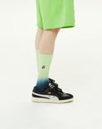 A person wearing a pair of black and green sneakers.