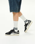 A man wearing a pair of black and white sneakers.