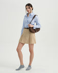 A woman in a blue shirt and tan skirt.