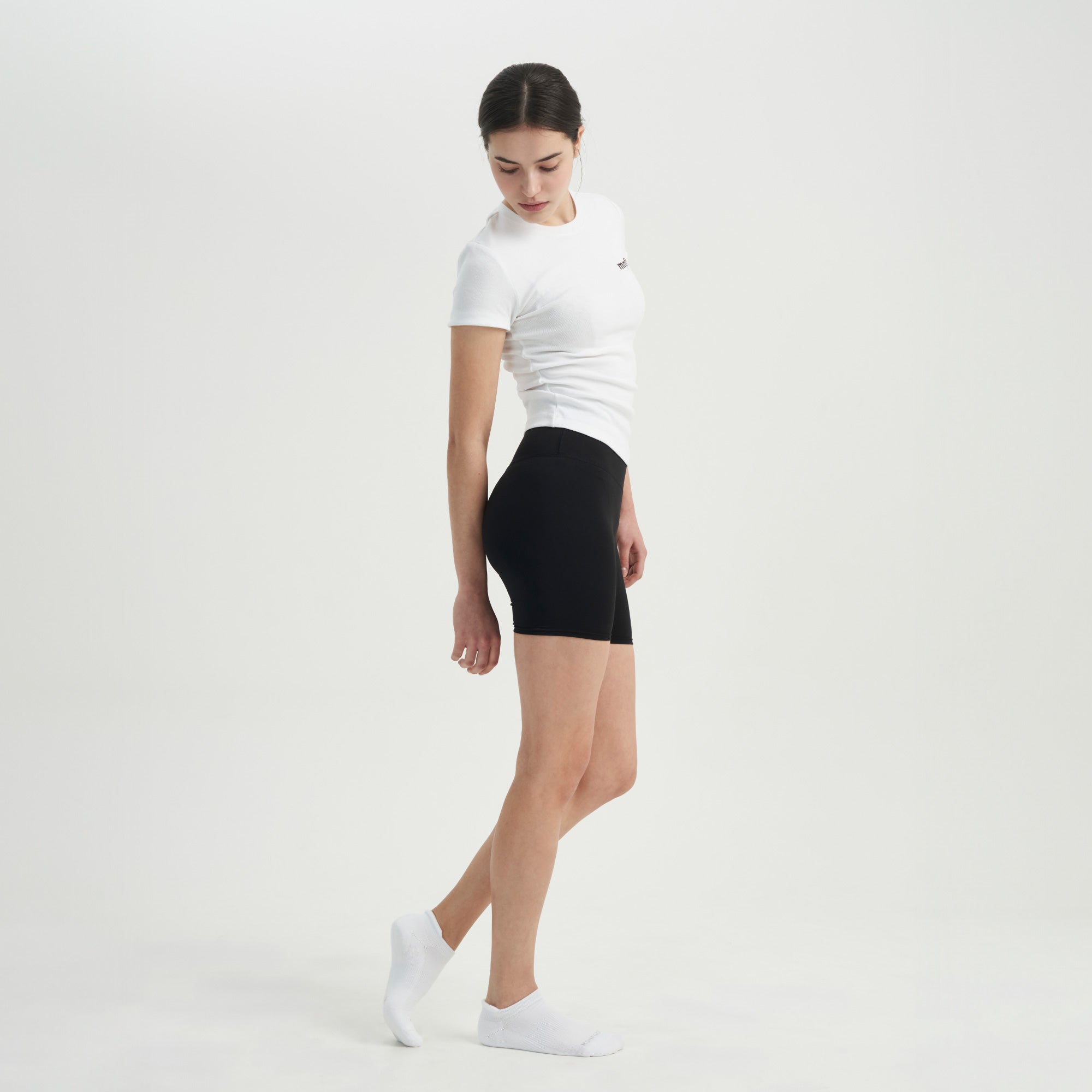 A woman in a white shirt and black shorts.