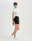 A woman in a white shirt and black shorts.