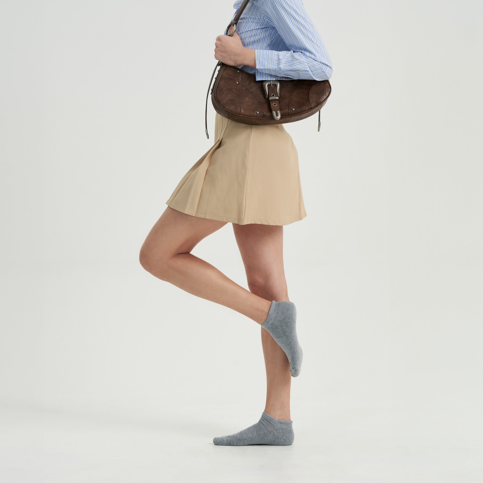 A woman is holding a brown purse and posing for a picture.