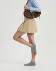 A woman is holding a brown purse and posing for a picture.