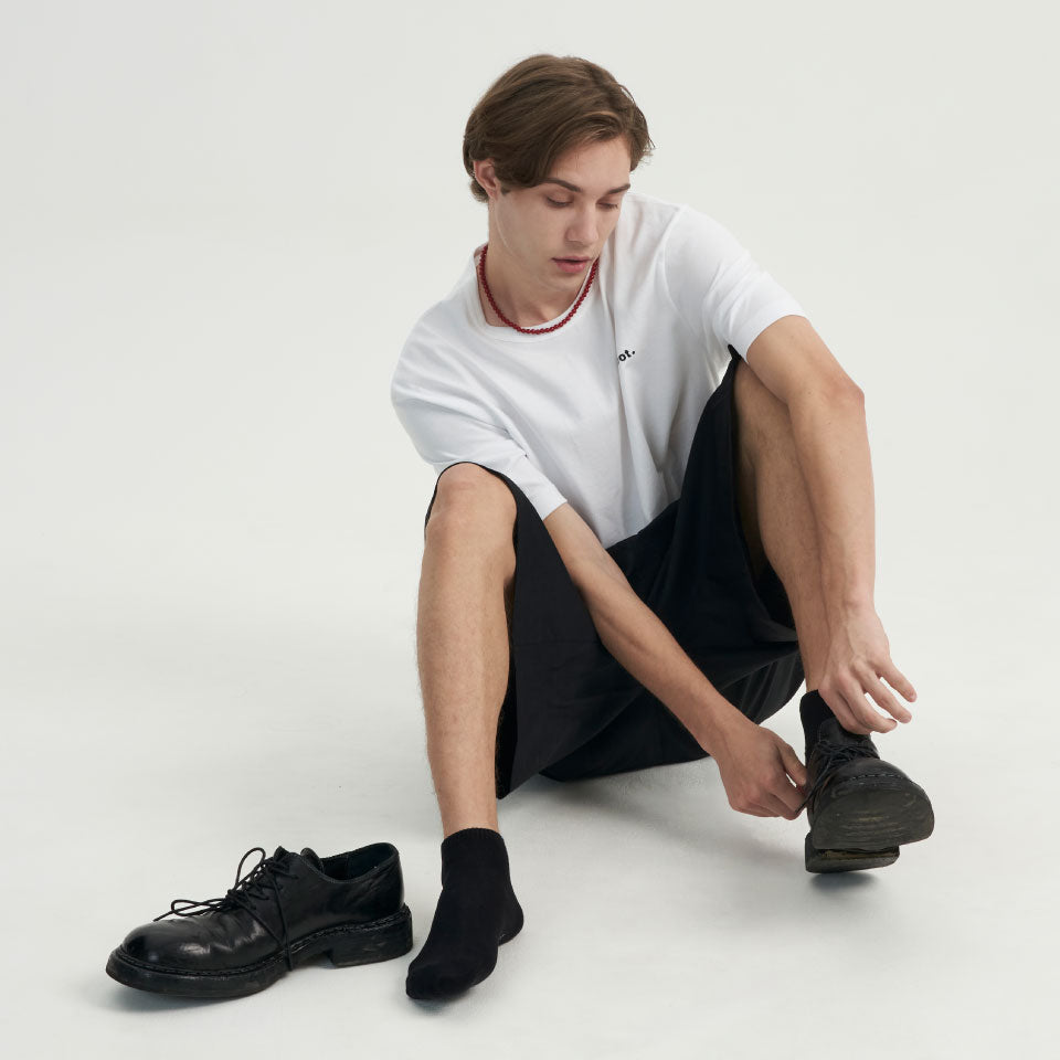 A man sitting on the ground with a pair of shoes.