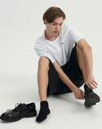 A man sitting on the ground with a pair of shoes.