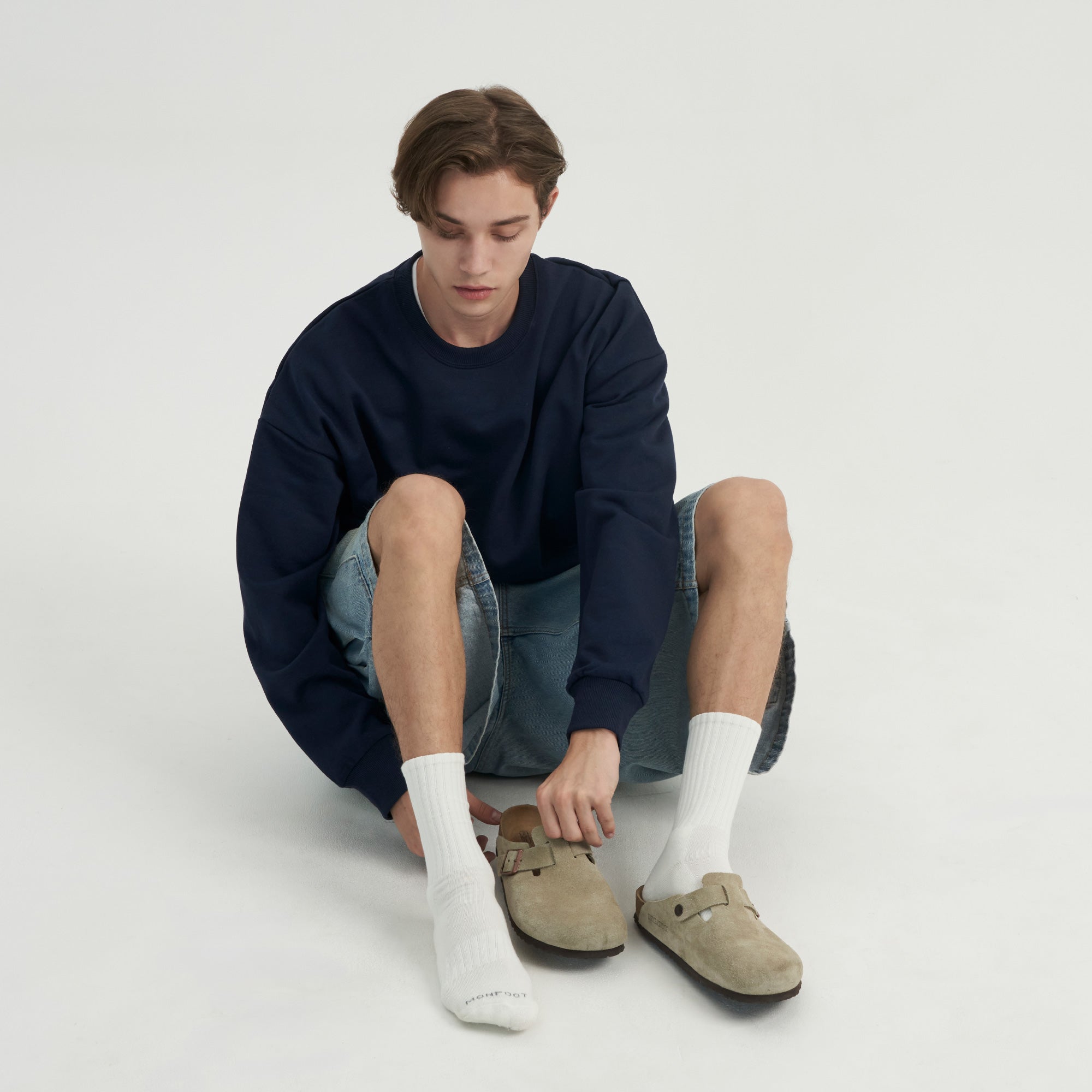 A young man sitting on the ground wearing a pair of shoes.