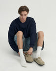 A young man sitting on the ground wearing a pair of shoes.