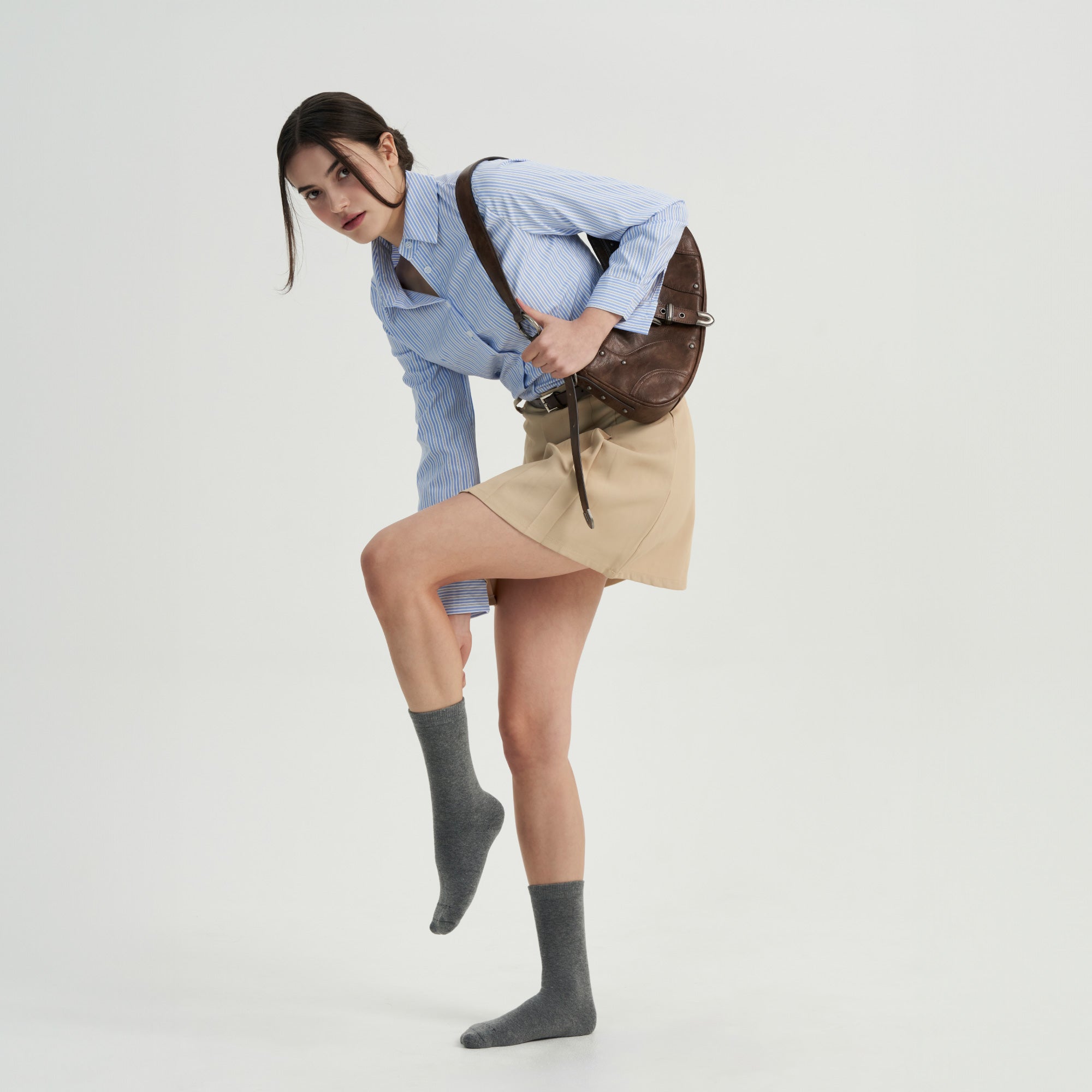 A woman in a skirt and shirt is posing for a picture.