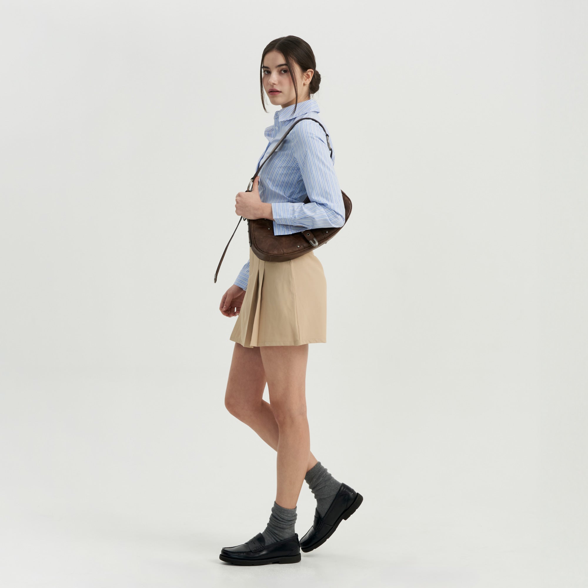 A woman in a blue shirt and tan skirt.