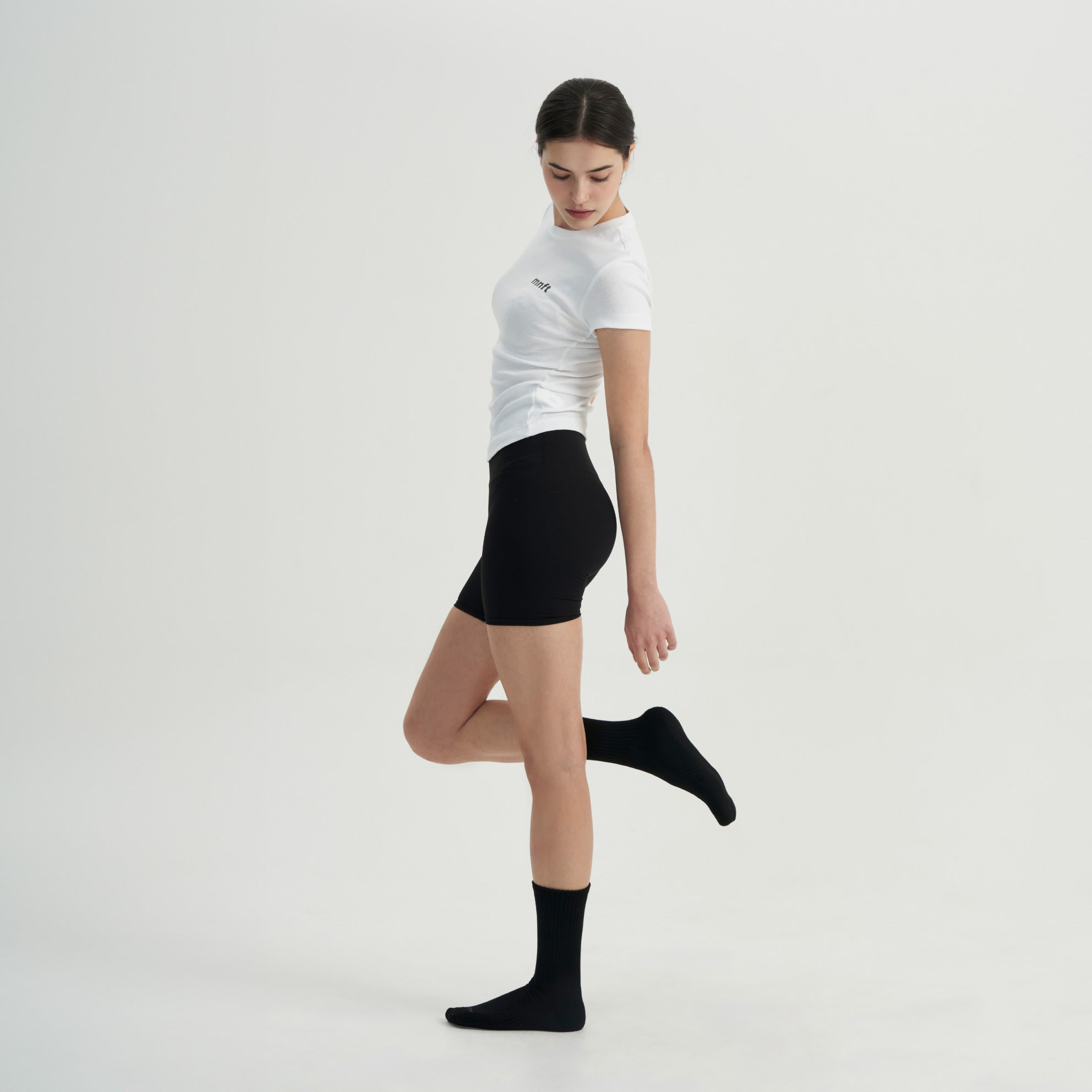 A woman in a white shirt and black shorts.