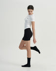 A woman in a white shirt and black shorts.
