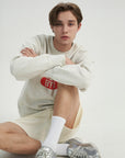 A young man sitting on the ground with his arms crossed.