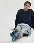 A young man sitting on the ground with his legs crossed.