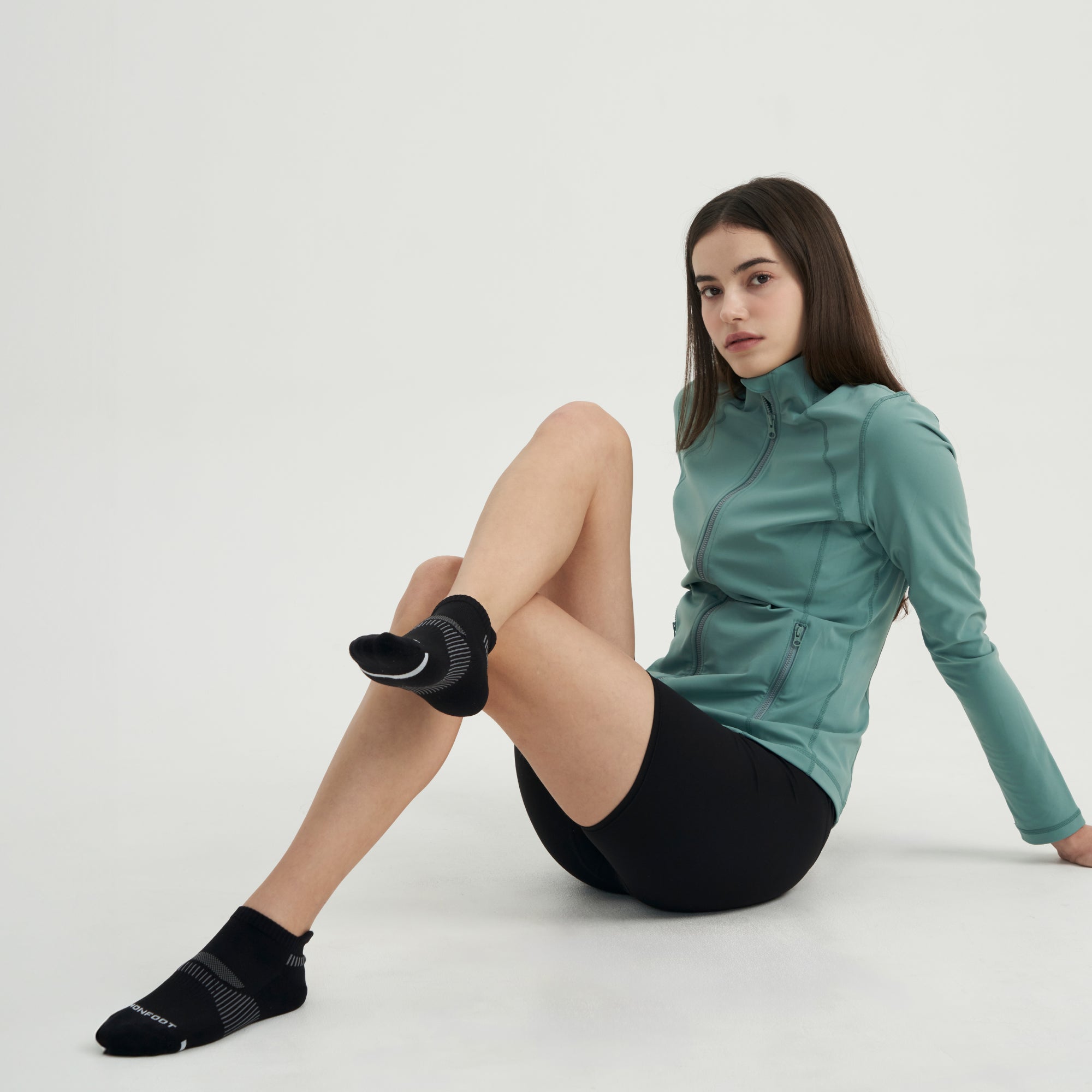 A woman sitting on the ground with her legs crossed.