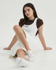 A woman sitting on the ground with her legs crossed.