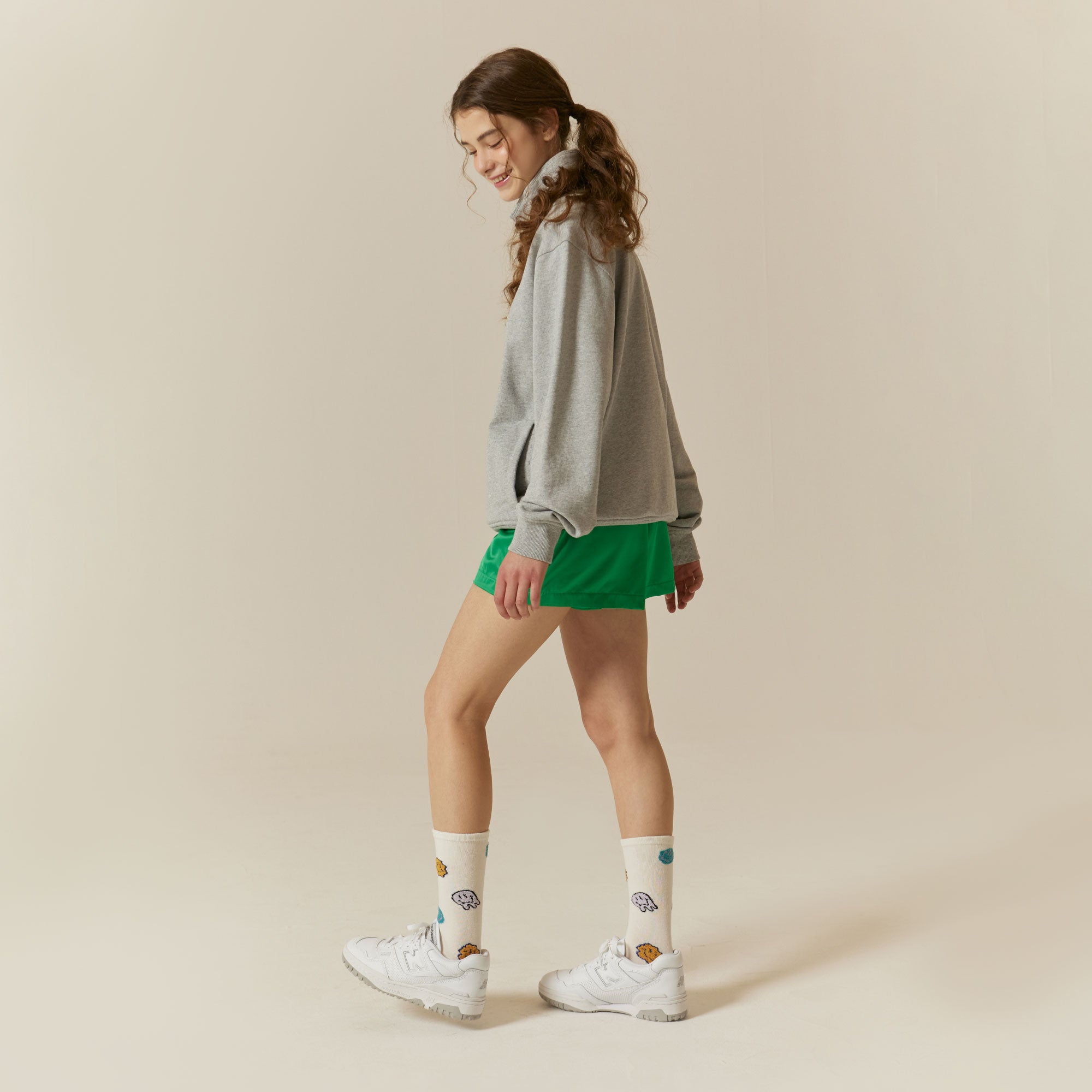 A woman in a grey sweatshirt and green shorts.