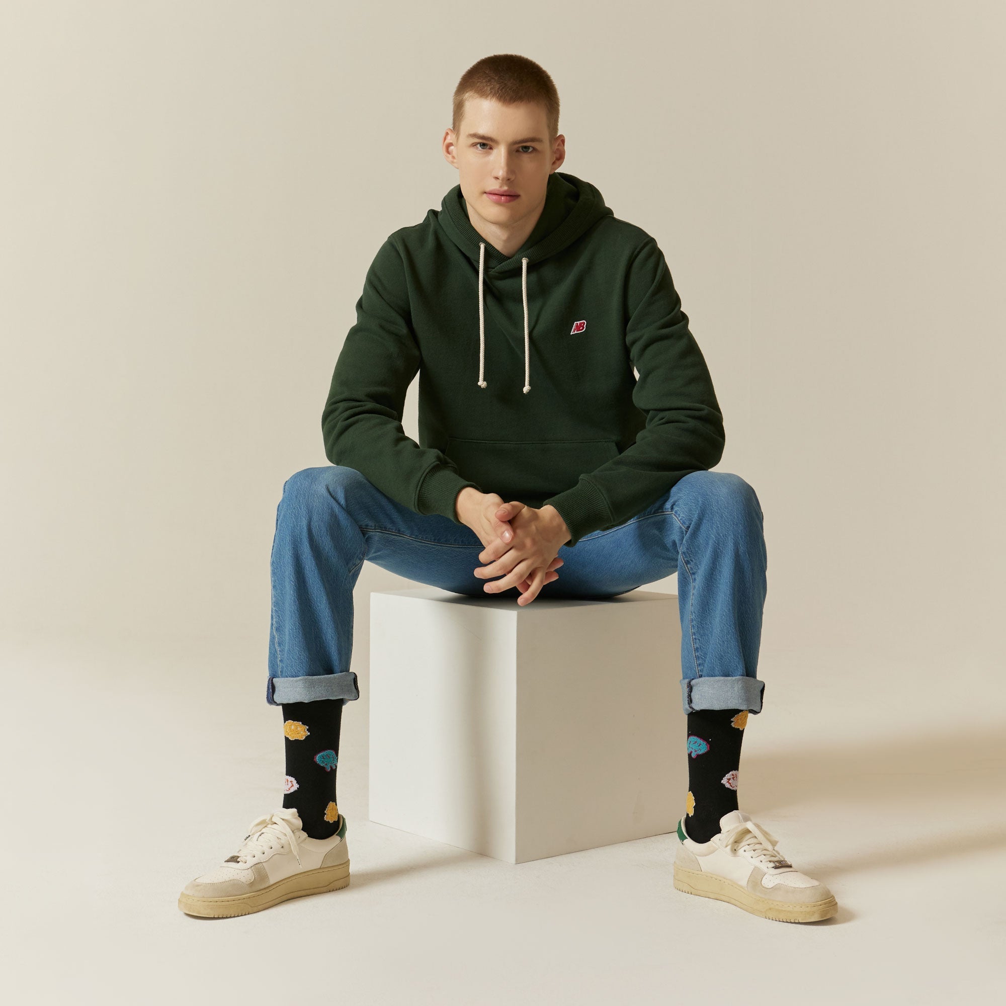 A man sitting on a stool wearing a green hoodie.