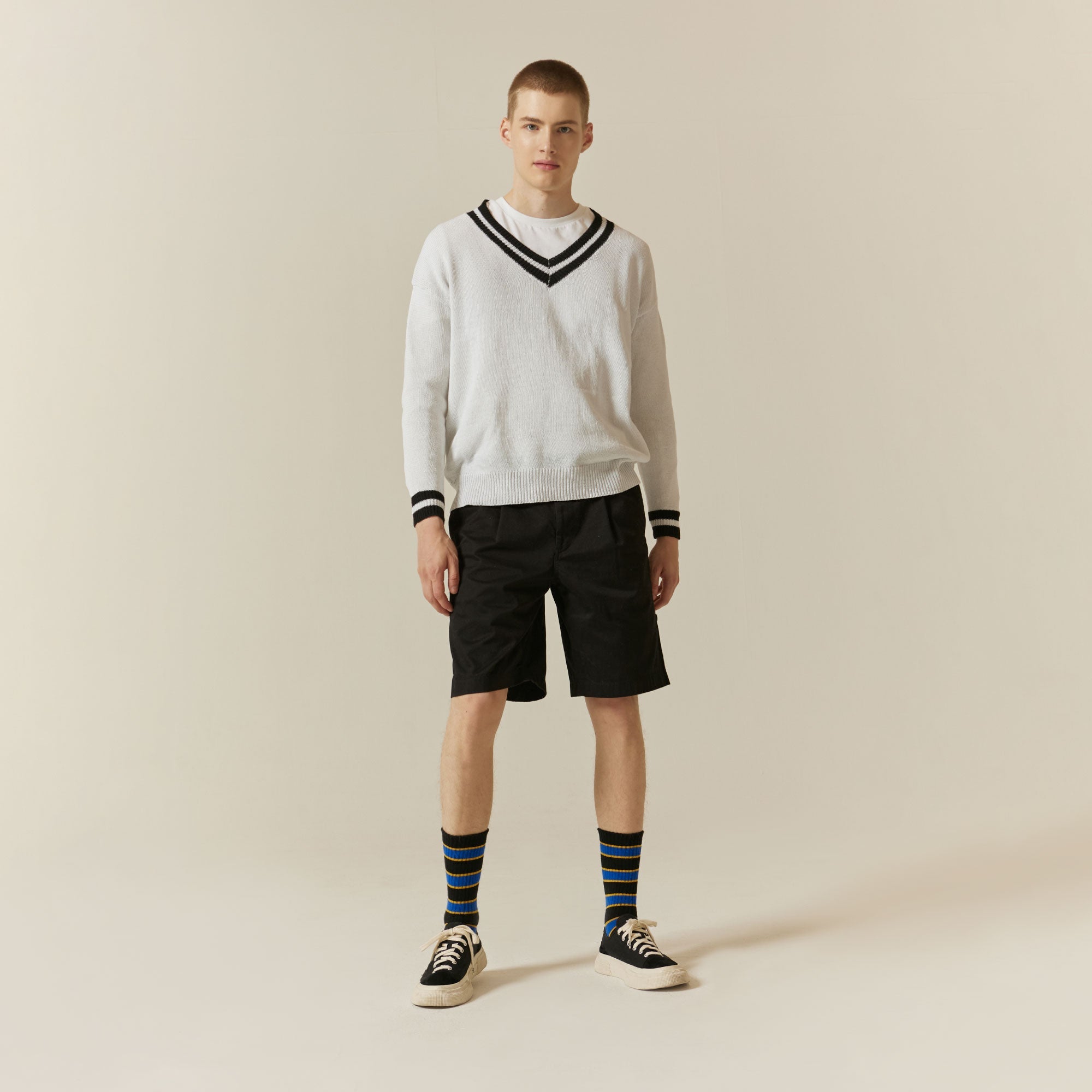 A man in a white sweater and black shorts.
