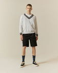 A man in a white sweater and black shorts.
