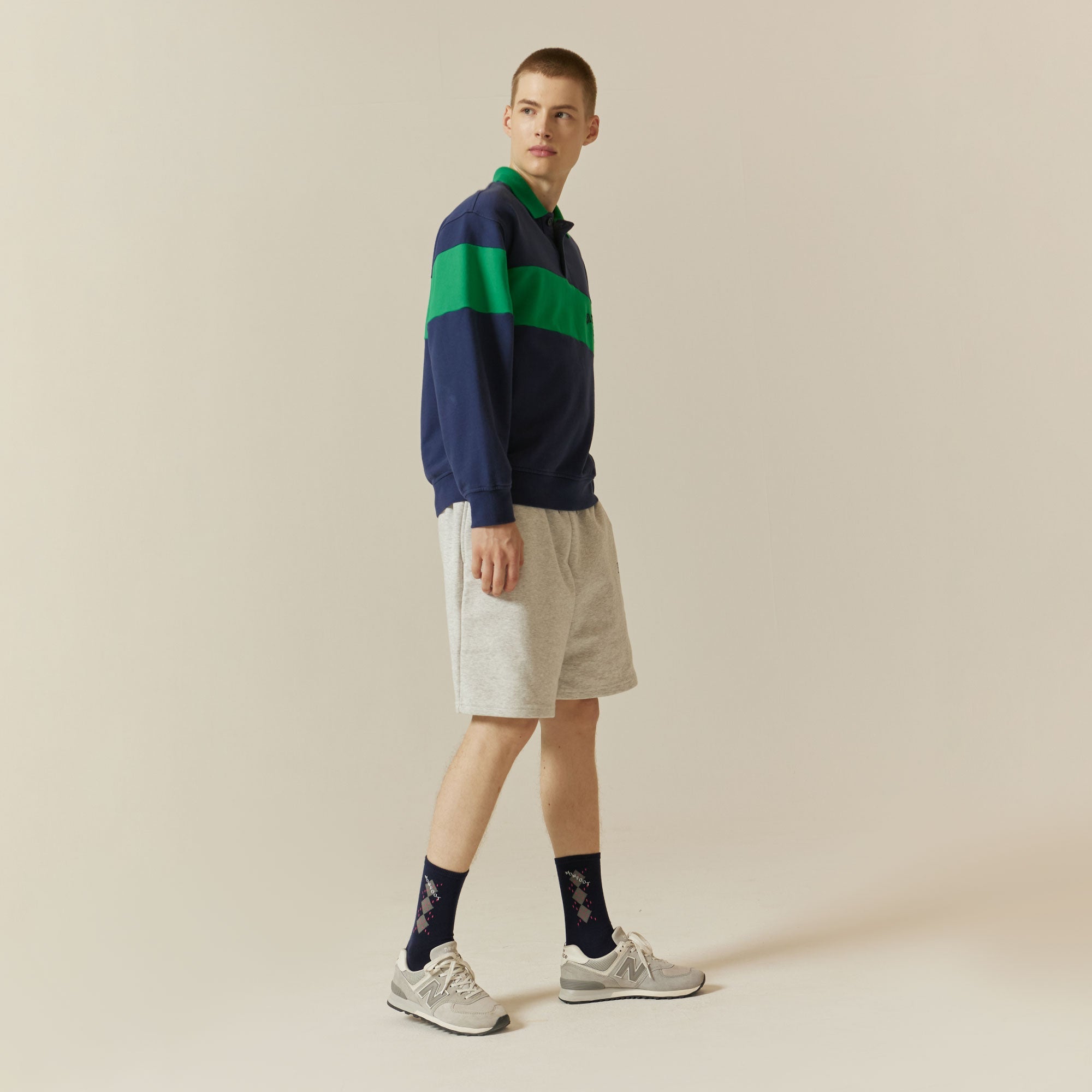 A man in a blue and green sweater and shorts.