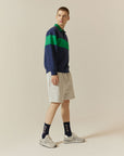 A man in a blue and green sweater and shorts.
