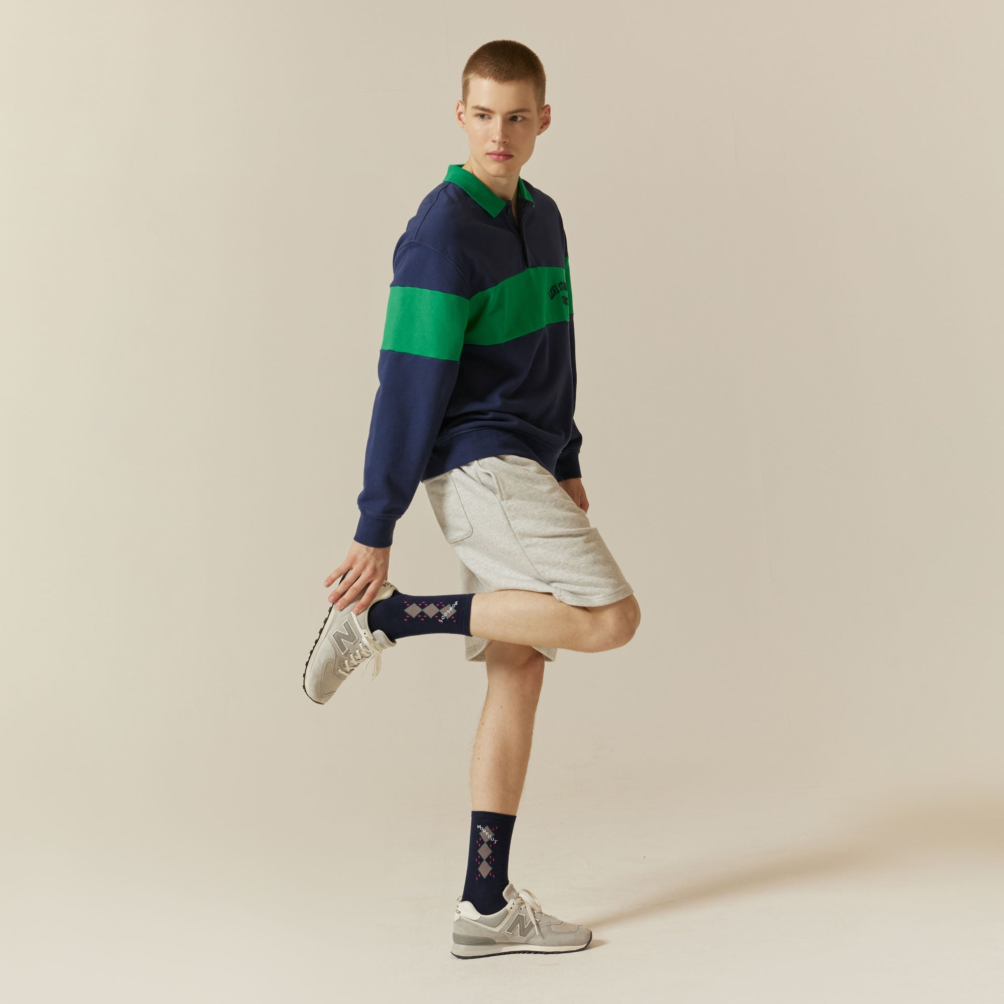 A man in a blue and green sweater and white shorts.
