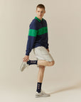 A man in a blue and green sweater and white shorts.