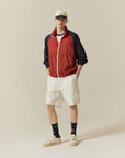 A man in a red jacket and white shorts.