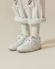 A person wearing white sneakers and white pants.