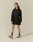 A woman in a black denim jacket and skirt.