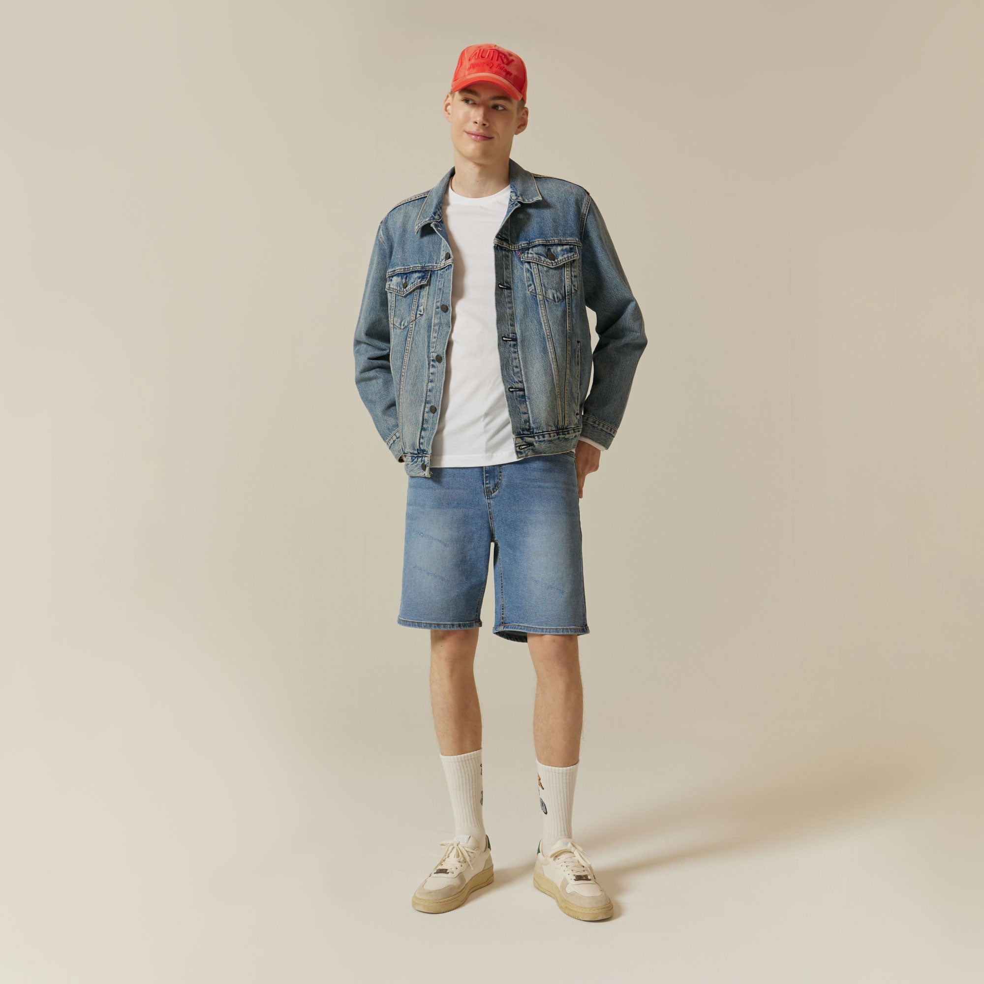 A man wearing a denim jacket and shorts.