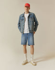A man wearing a denim jacket and shorts.