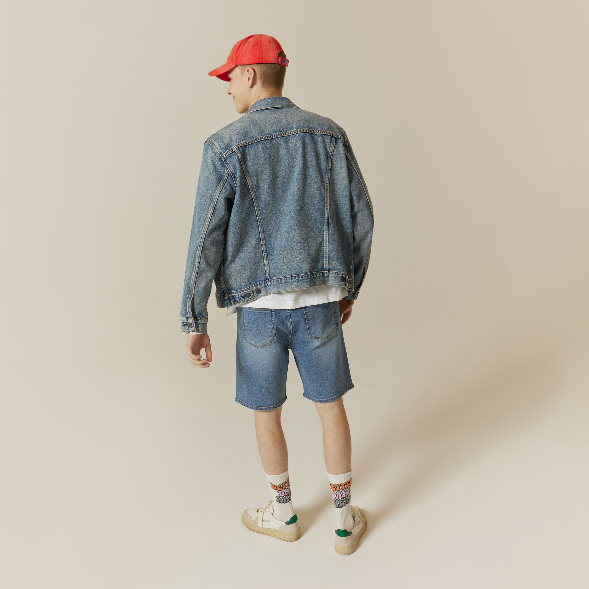 A man wearing a denim jacket and shorts.