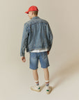 A man wearing a denim jacket and shorts.