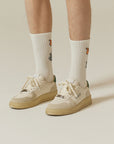 A person wearing a pair of white tennis shoes.