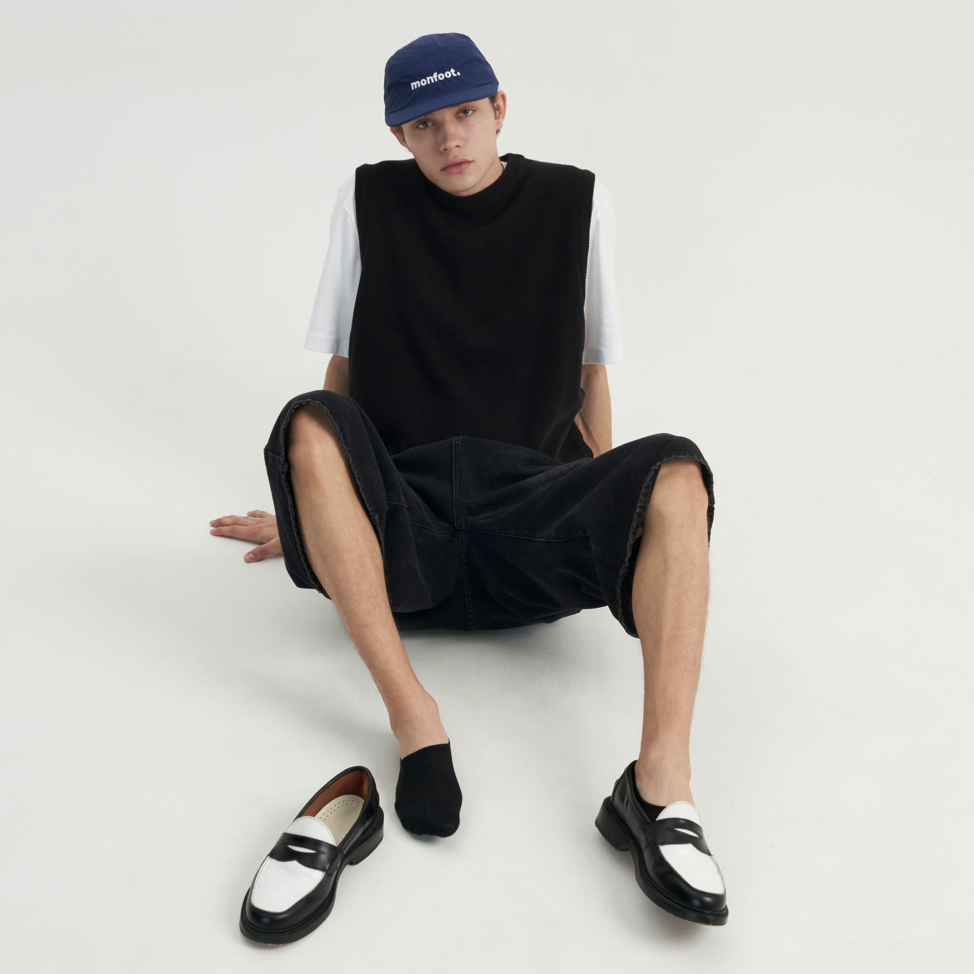 A man sitting on the ground wearing a hat.