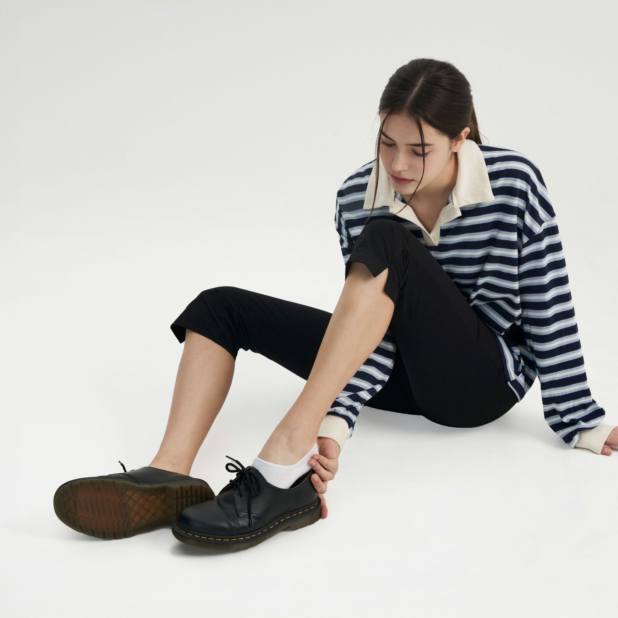 A woman sitting on the ground with her legs crossed.