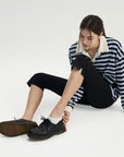 A woman sitting on the ground with her legs crossed.