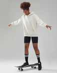 A young man riding a skateboard on a white surface.