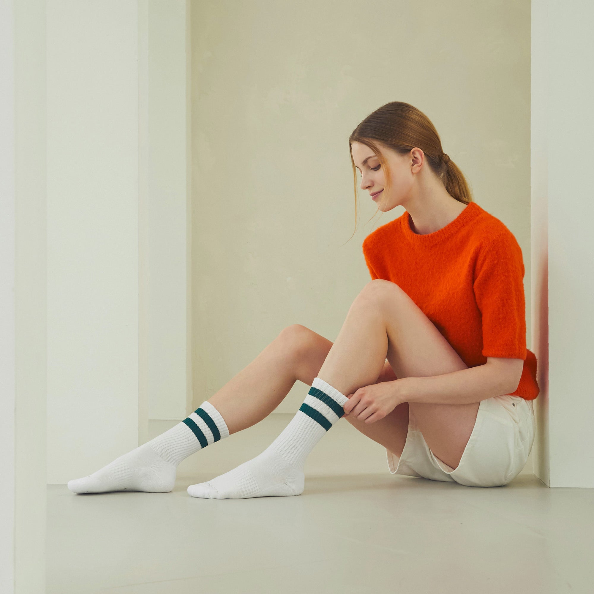 A woman sitting on the floor with her legs crossed.