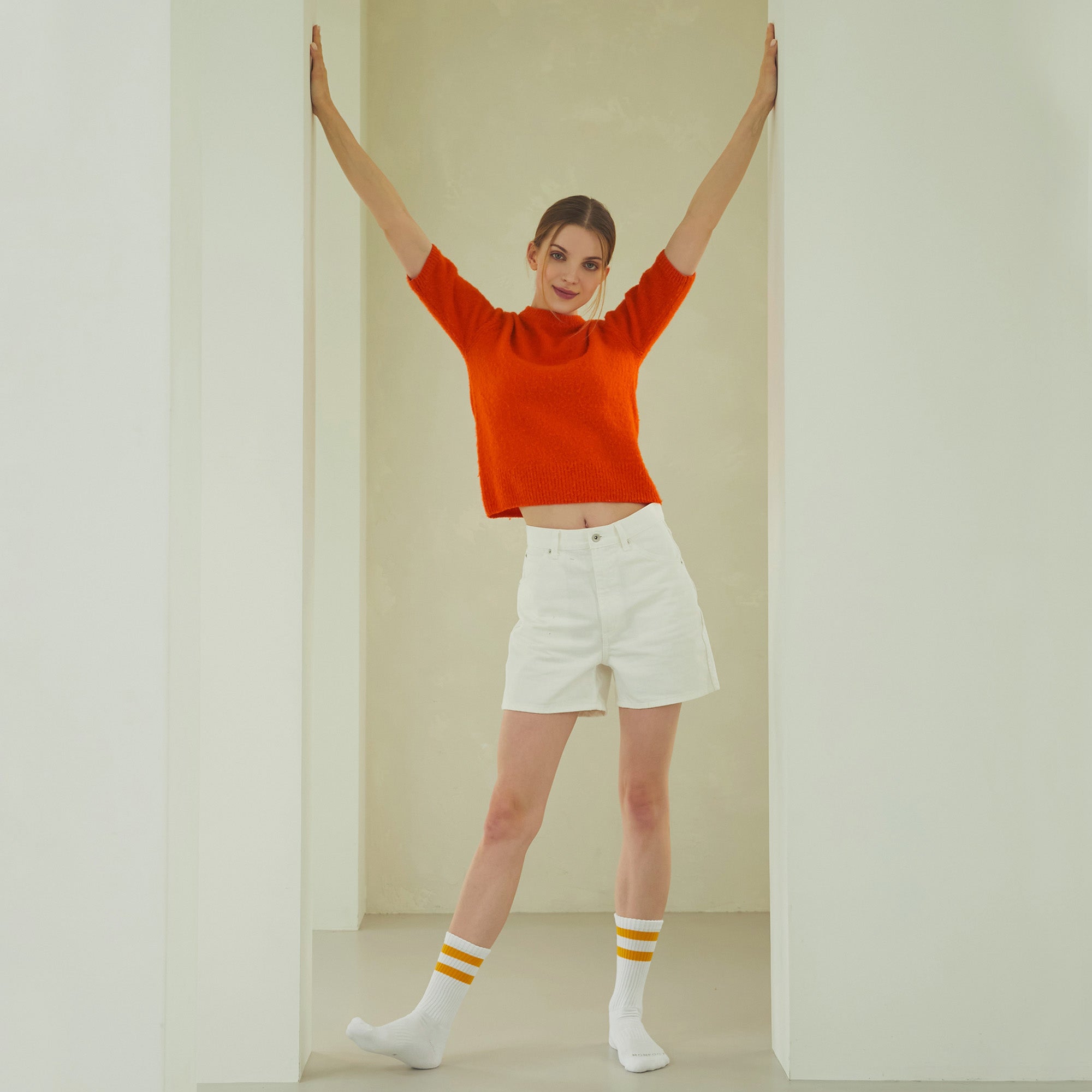 A woman standing in a room with her arms in the air.