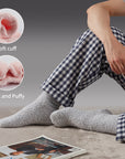 A person sitting on the floor with their feet on a coffee cup.