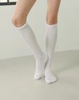 A woman in a short skirt and knee high socks.