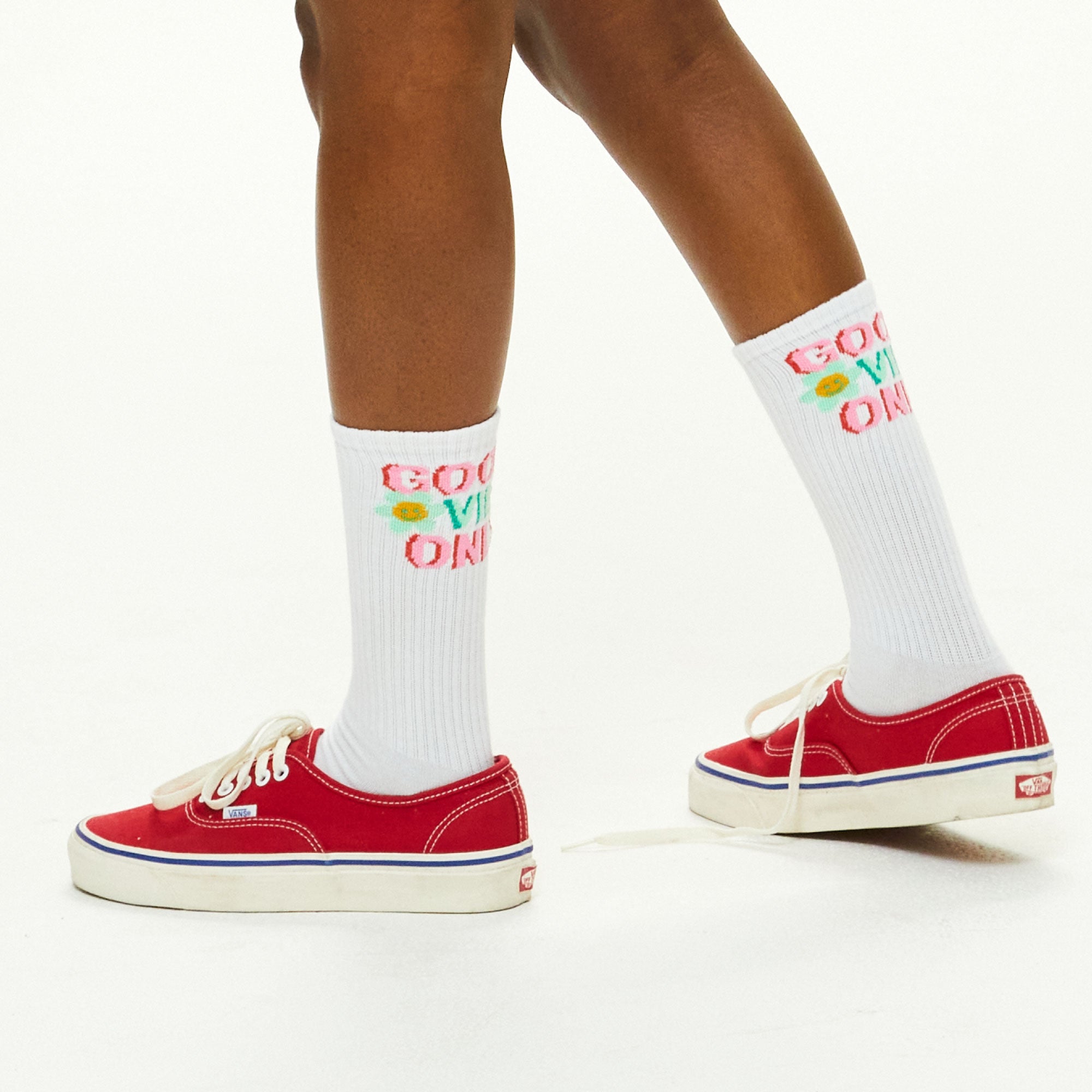 A close up of a person wearing red shoes.