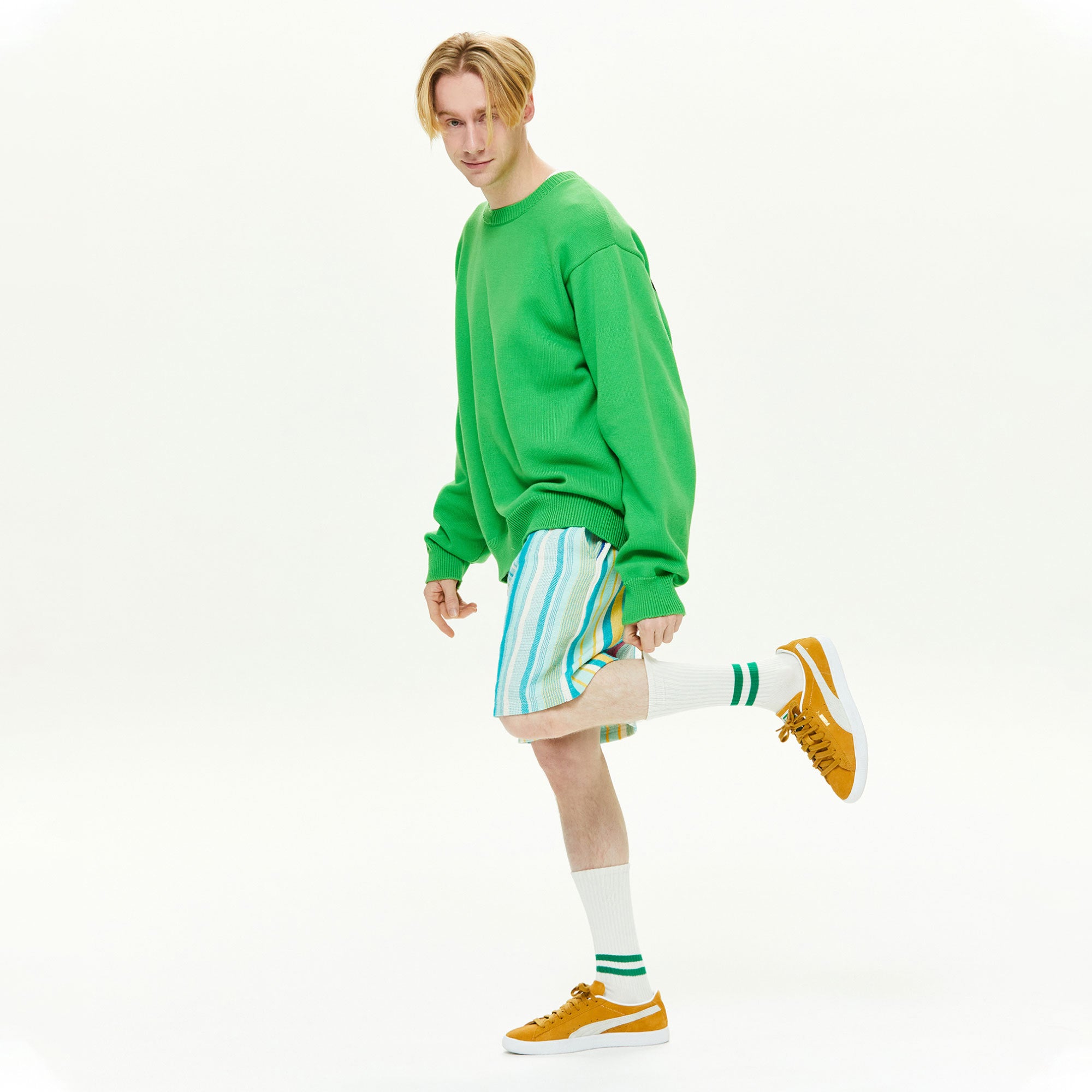 A man in a green sweater and striped shorts.
