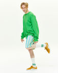 A man in a green sweater and striped shorts.
