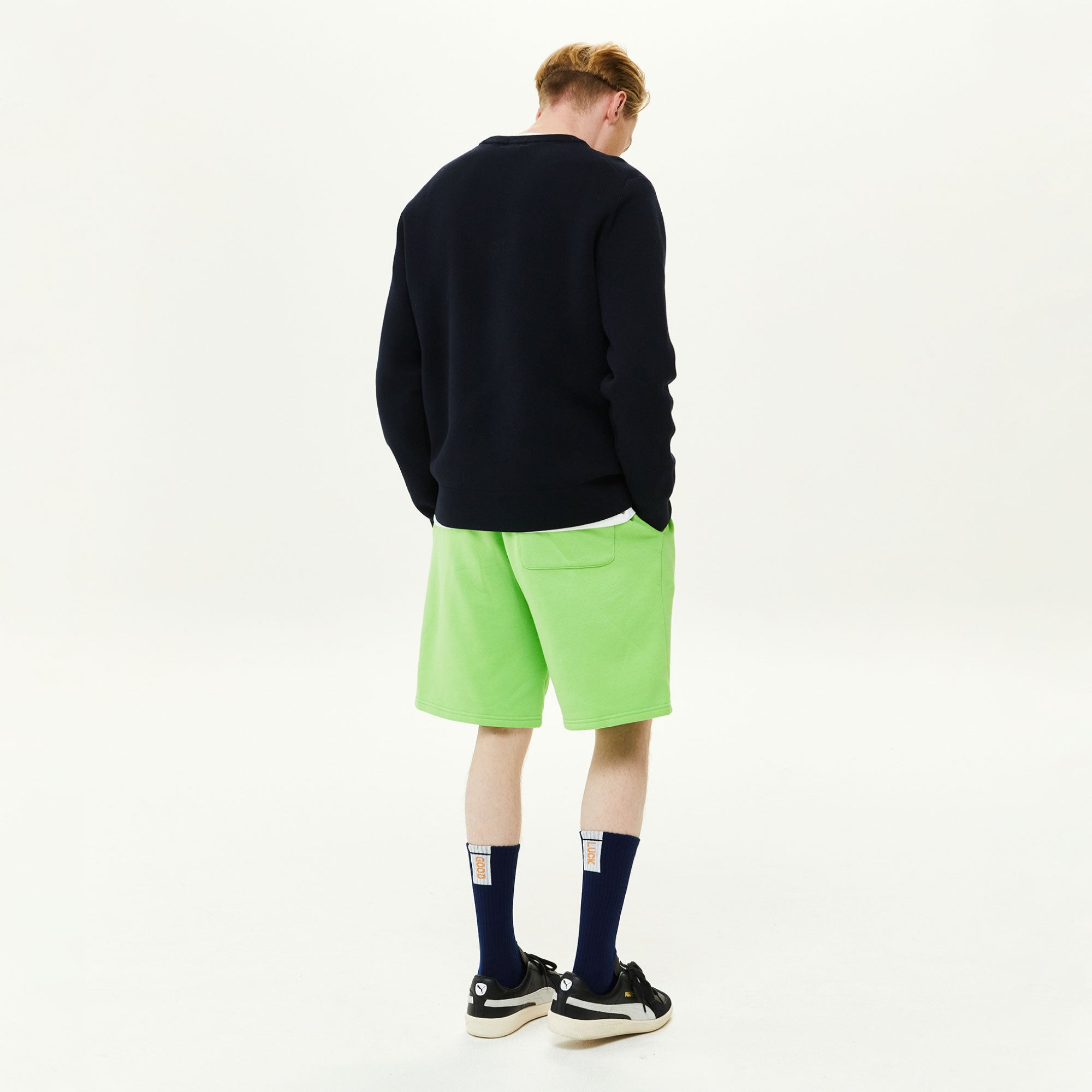 A man in a black sweater and green shorts.