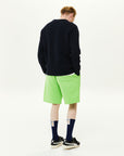 A man in a black sweater and green shorts.