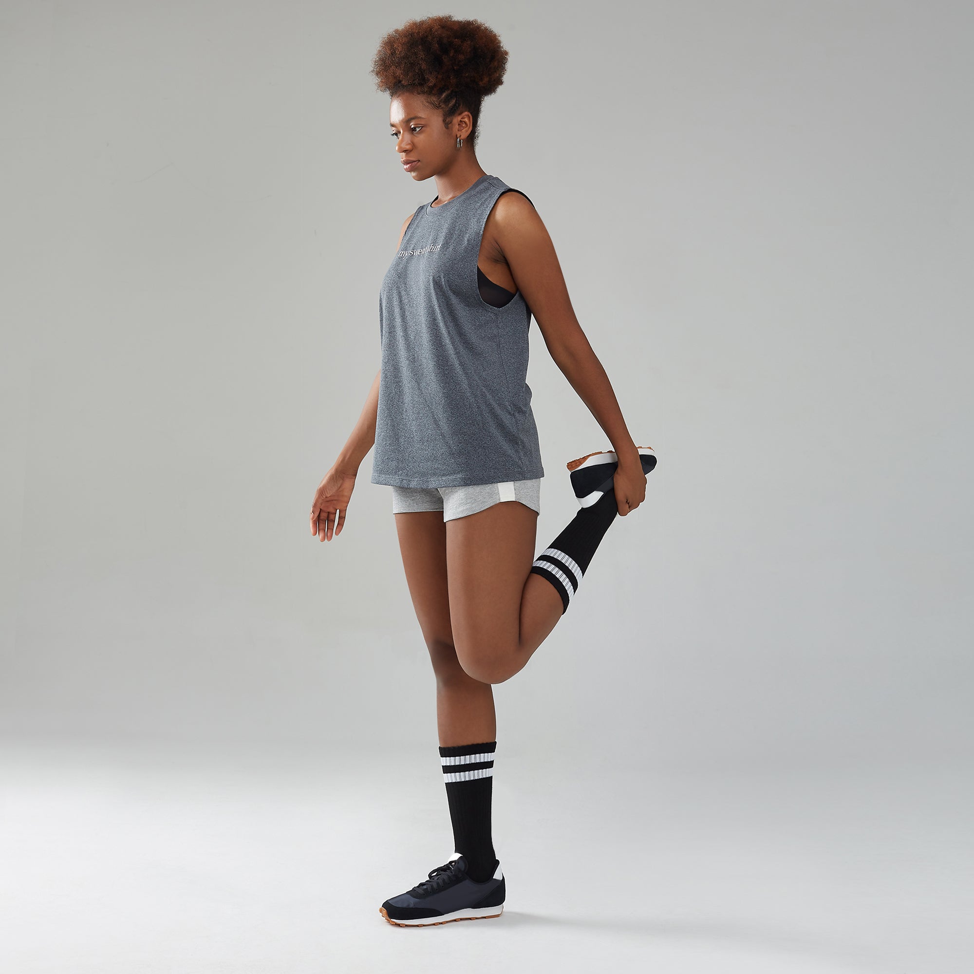 A woman in shorts and a tank top posing for a picture.